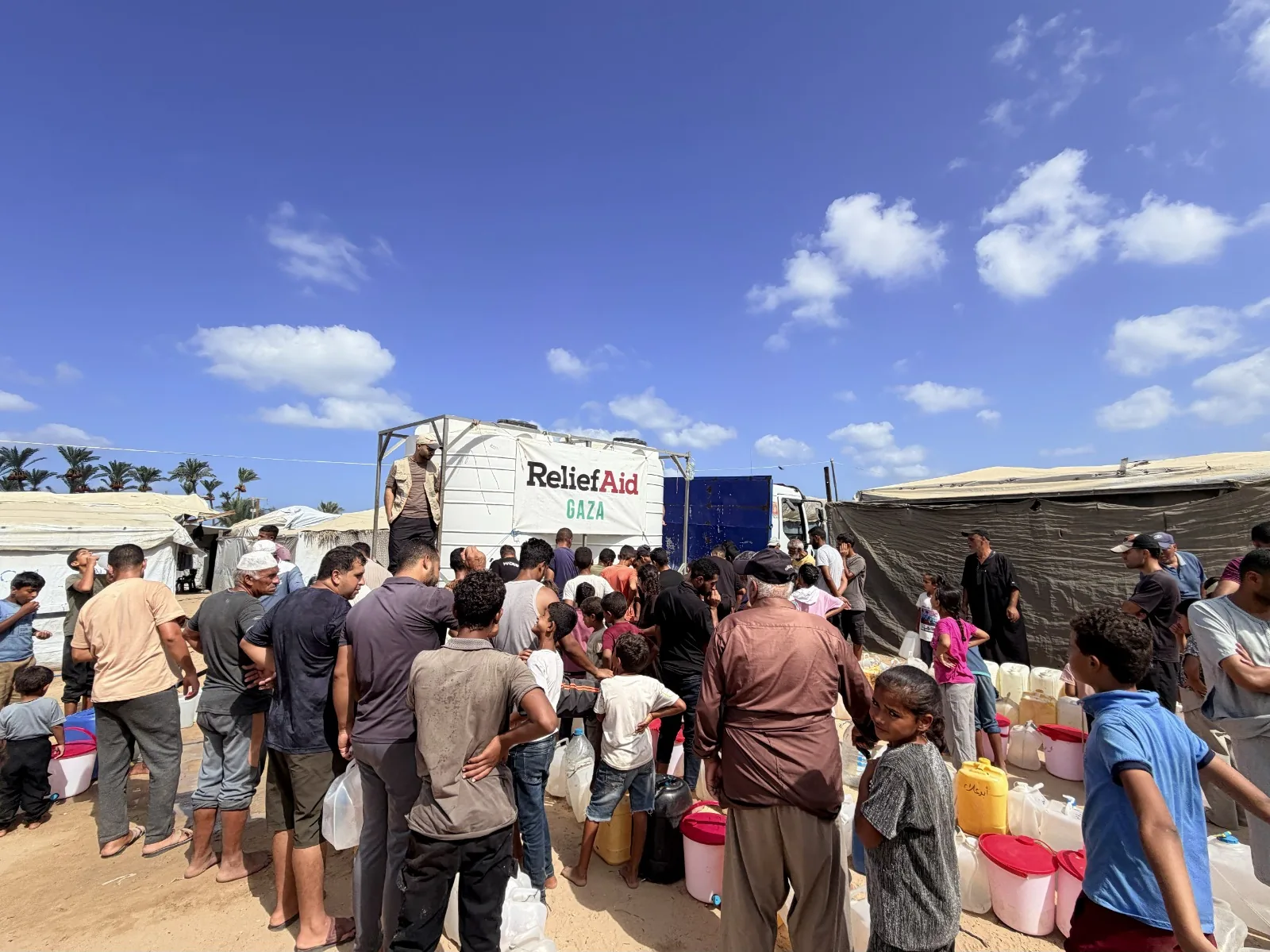 Families collect water at a ReliefAid distribution point in Gaza