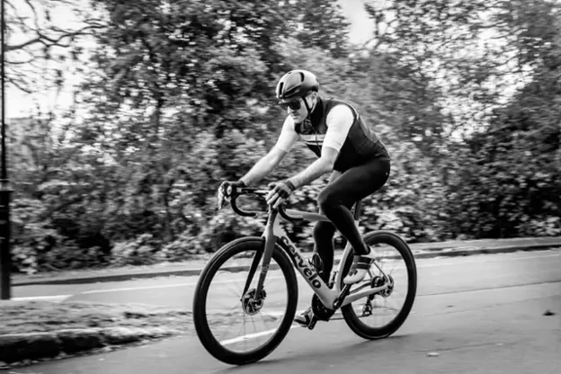 A lone cyclist riding through parkland, in black and white